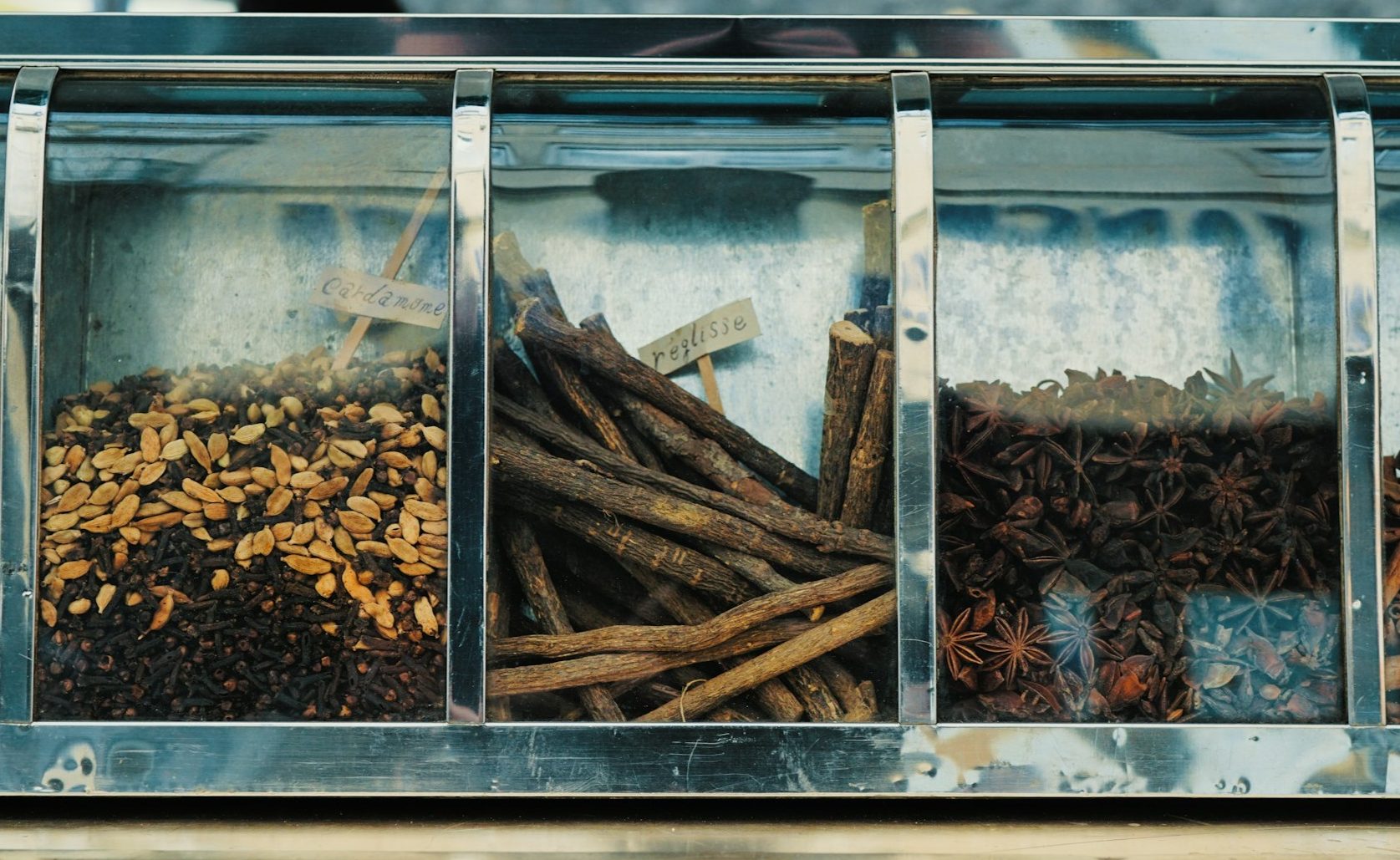 Various flavor items in a cabinet like cinnamon sticks and vanilla.