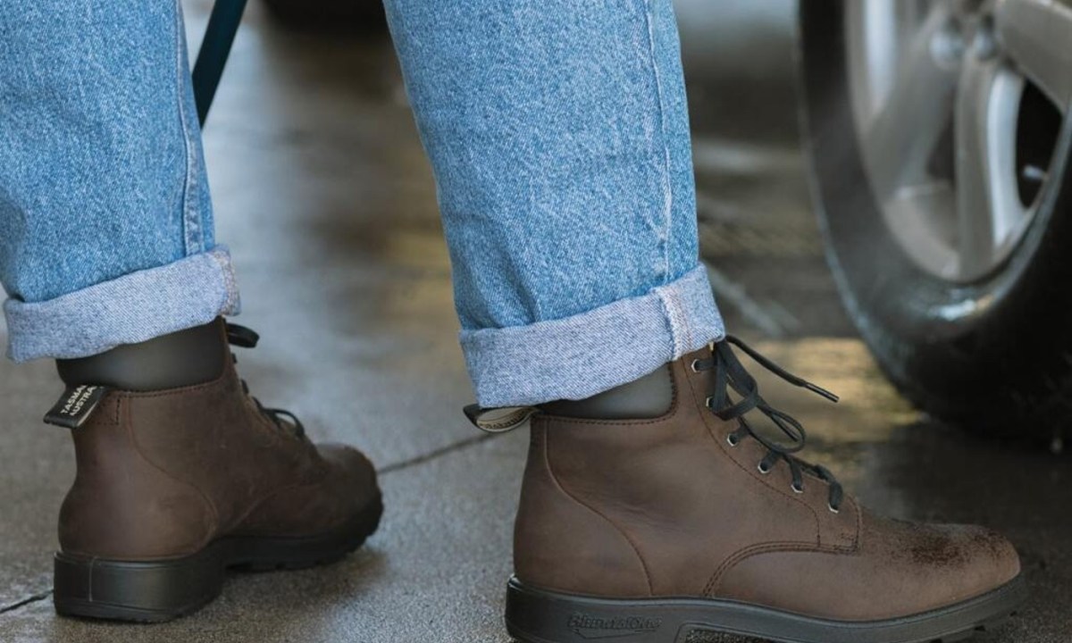 person wearing brown lace up boots next to car